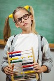 Cute pupil holding abacus in a classroom