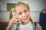Smiling pupil phoning with smartphone in a classroom 