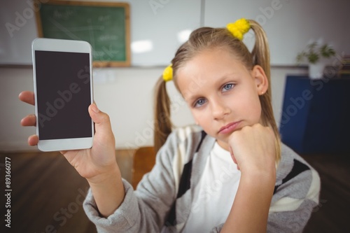 Cute pupil showing smartphone to camera