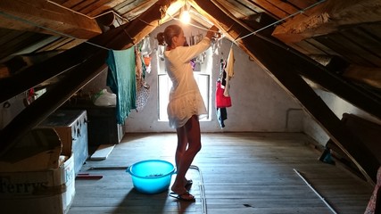 Mujer tendiendo ropa en la buhardilla