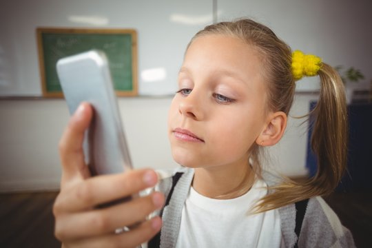 Cute Pupil Using Smartphone In A Classroom 