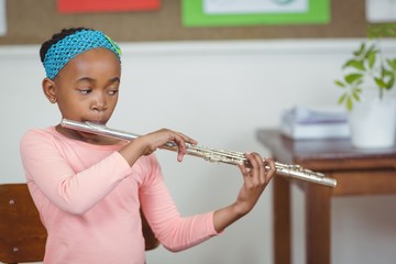 Cute pupil playing flute in a classroom © WavebreakMediaMicro