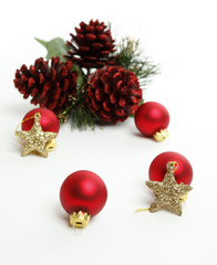 Christmas Balls with gold stars and red pine cones in the background. Focus is on closest star.