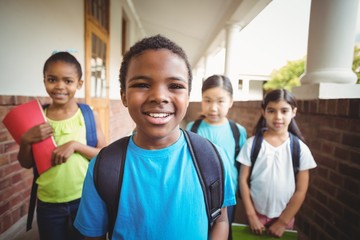 Cute pupils holding notebooks at corridor