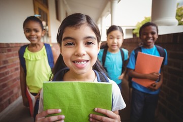 Cute pupils holding notebooks at corridor