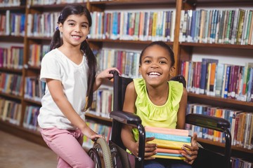 Smiling pupil in wheelchair holding books in the library