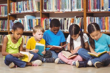 Pupils sitting on the ground and reading books in the library