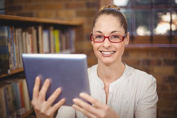 Blonde teacher using tablet in the library