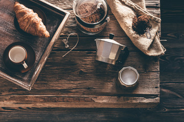 Coffee preparation on old wooden table in evening window light - obrazy, fototapety, plakaty