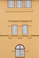 Closed wooden windows on orange building.