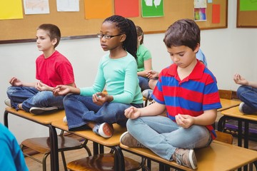 Pupils meditating on classroom desks