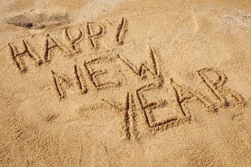 The words Happy New Year written in the sand on the beach