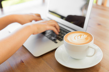 Closeup of business woman hand typing on laptop keyboard and cof