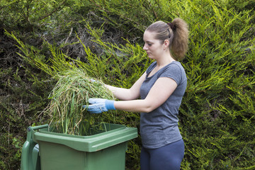 Girl with grass near green bin