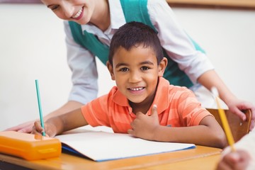 Teacher helping a little boy during class