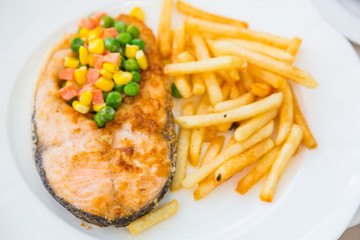 Grilled salmon steak meal served with salad and French fries
