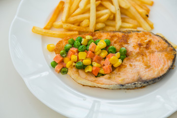 Grilled salmon steak meal served with salad and French fries