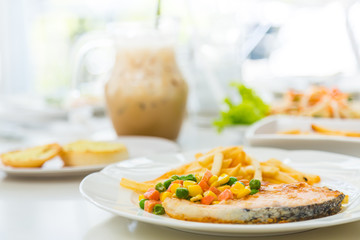 Grilled salmon steak meal served with salad and French fries