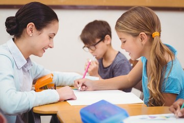 Teacher helping a little girl during class