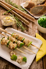Concept of outdoor barbecue picnic food. Chicken and peppers shish-kebabs or souvlaki on skewers on a rustic wood table