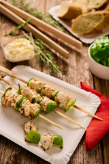 Concept of outdoor barbecue picnic food. Chicken and peppers shish-kebabs or souvlaki on skewers on a rustic wood table