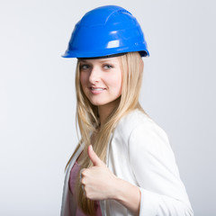 Junge Ingenieurin mit Helm und Daumen hoch