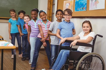 Disabled pupil smiling at camera with classmates 