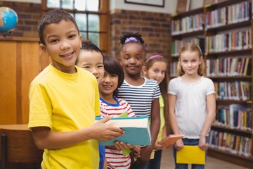 Pupils holding books from shelf in library