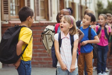 Cute pupils with schoolbags outside