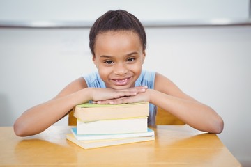 Smiling pupil resting head on a stack of books