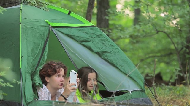 Girls and the little boy admire the nature lying in tent.