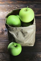 Äpfel der Sorte Delbar in einer Papiertüte auf Holzhintergrund