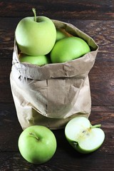 Äpfel der Sorte Delbar in einer Papiertüte auf Holzhintergrund