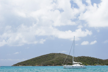 A sailboat in the carribean with island behind.