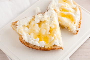 bread with cheese and honey on white chopping board