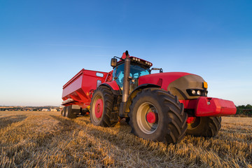 Agriculture tractor and trailer on a stubble field, copy space for text