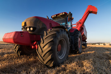 Close up view of  a red agriculture tractor at stubble field