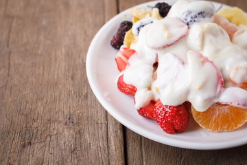 fruit salad with cream,  banana, strawberry, orange, mulberry.