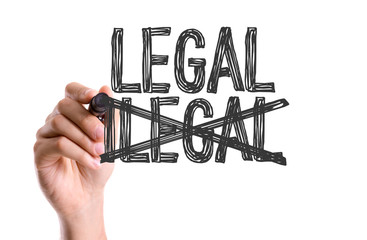 Hand with marker writing the word Legal/Ilegal