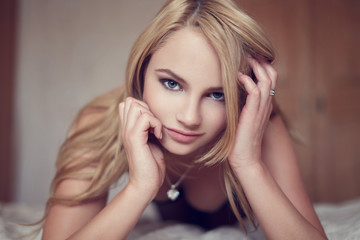 Naklejka premium Sexy blonde woman elbowing on bed