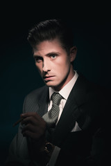 Cigar smoking retro 40s businessman in suit and tie. Hair combed back.