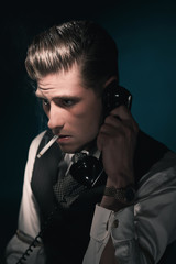 Vintage stylish detective in waistcoat and tie calling and smoking cigarette.