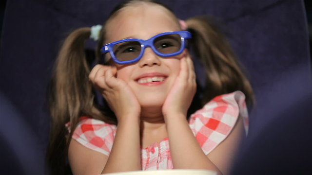 Beautiful little girl waching movie in the cinema