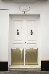 Puerta blanca con chapas doradas.