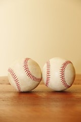 Objects: Two baseballs on a wood table, vertical