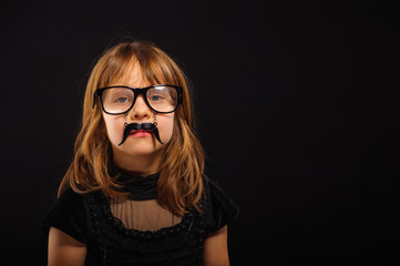 Fototapeta na wymiar Young girl at Halloween party with spectacles and fake mustache