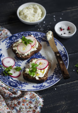 sandwiches with cream cheese and radish on a vintage plate on a dark wooden background