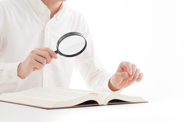 虫眼鏡を使って読書をしている男性