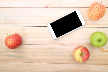 Smartphone and apple on wood table background. Top view with copy space