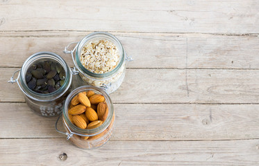 Pumpkin seed, oats and almond in jars on a wooden table, up view